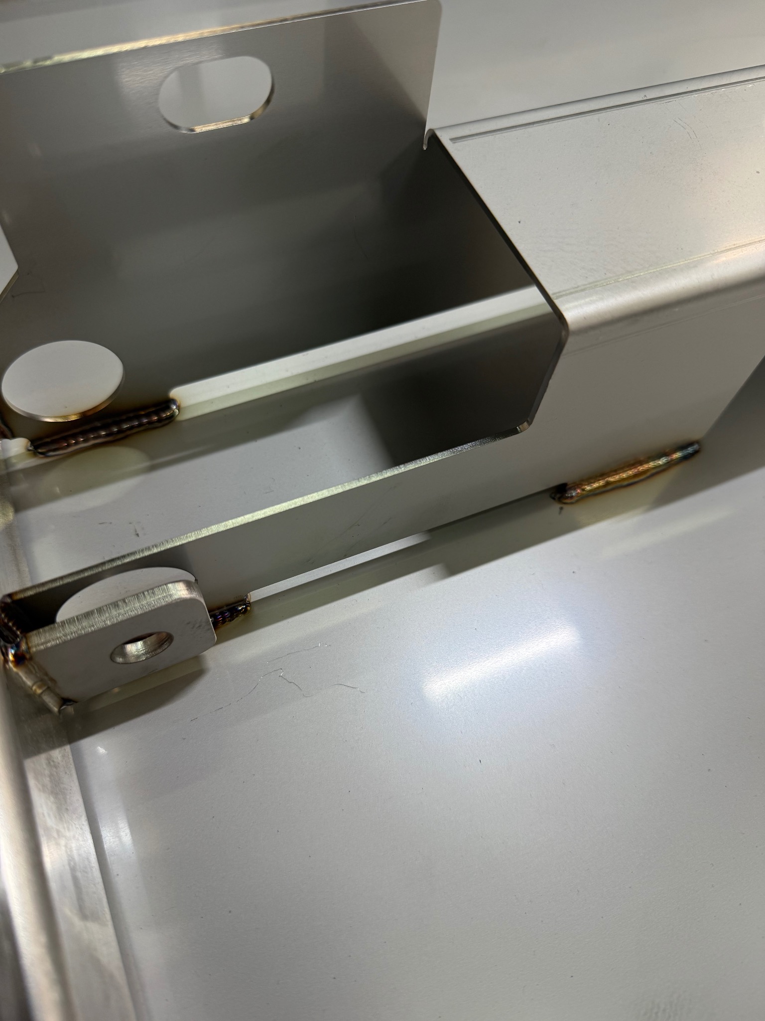 Detal metalowej konstrukcji po spawaniu, widoczne spawy łączące elementy. Jasne tło, precyzyjne wykonanie, widoczne detale spoin.