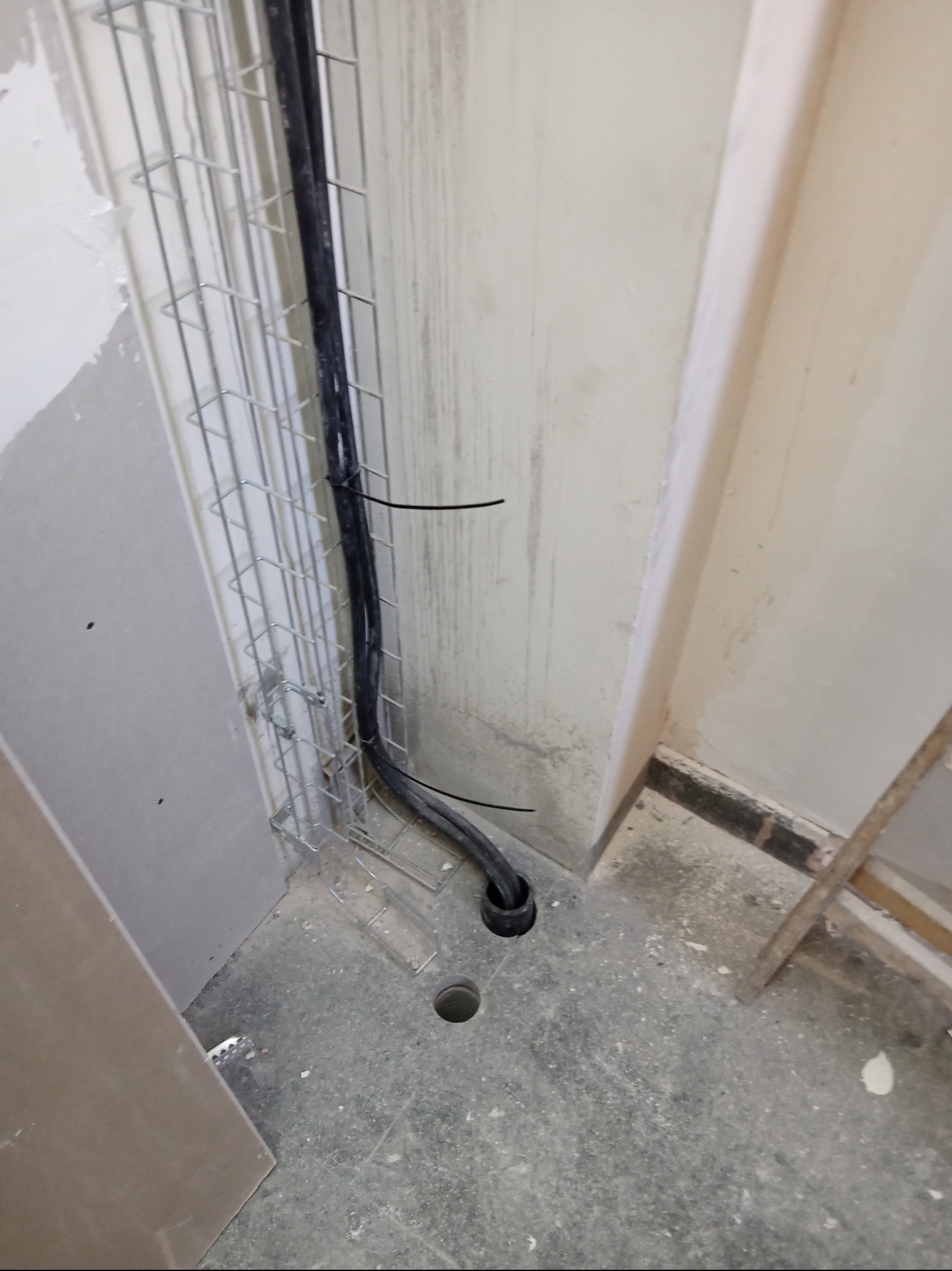 Montaż kabli elektrycznych w metalowej korycie przymocowanej do ściany, przewody zabezpieczone czarnymi opaskami zaciskowymi.