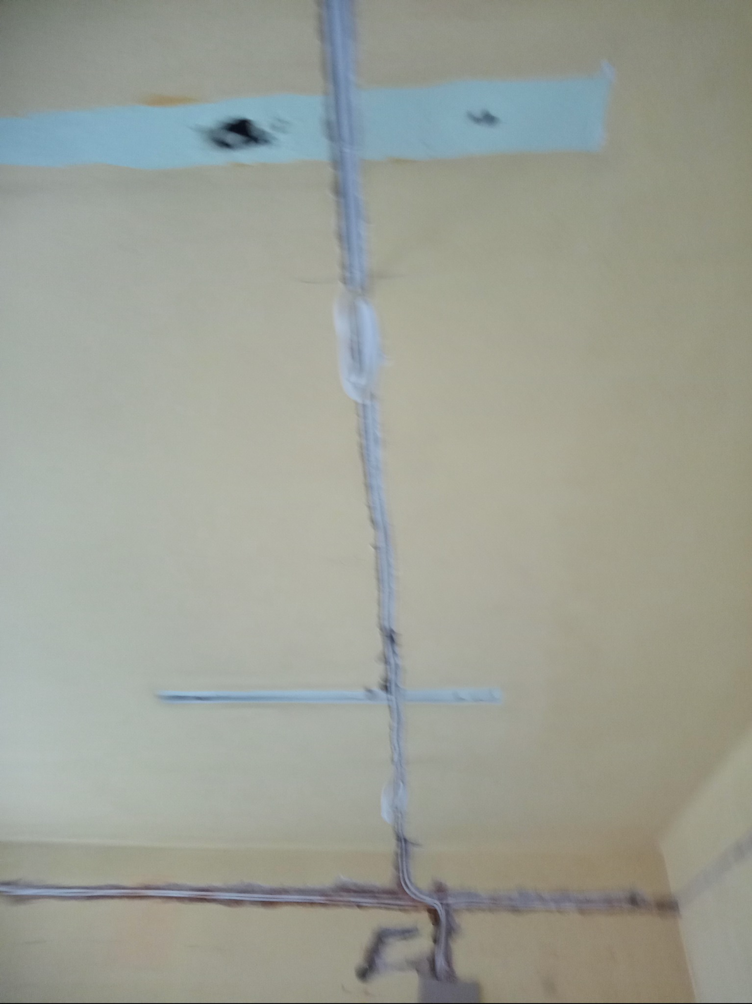 Wewnętrzna instalacja elektryczna, kable prowadzone po powierzchni ściany i sufitu, widoczne ślady po wcześniejszych pracach malarskich.