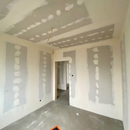 Wall Done Szymon Andrysiak - Pokój w trakcie prac wykończeniowych: ściany i sufit częściowo pokryte szpachlą, widoczne łączenia płyt gipsowo-kartonowych, zabezpieczona podłoga.