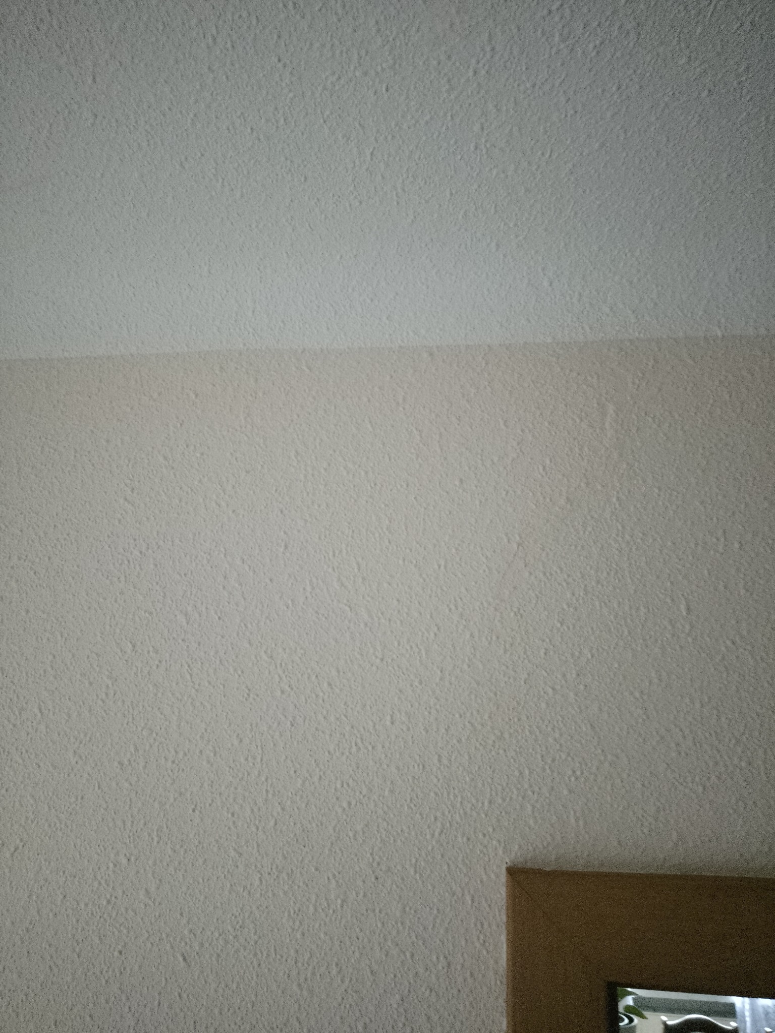 Tekstura ściany i sufitu po nałożeniu gładzi w Starachowicach, dolny róg kadru pokazuje fragment ramy lustra.