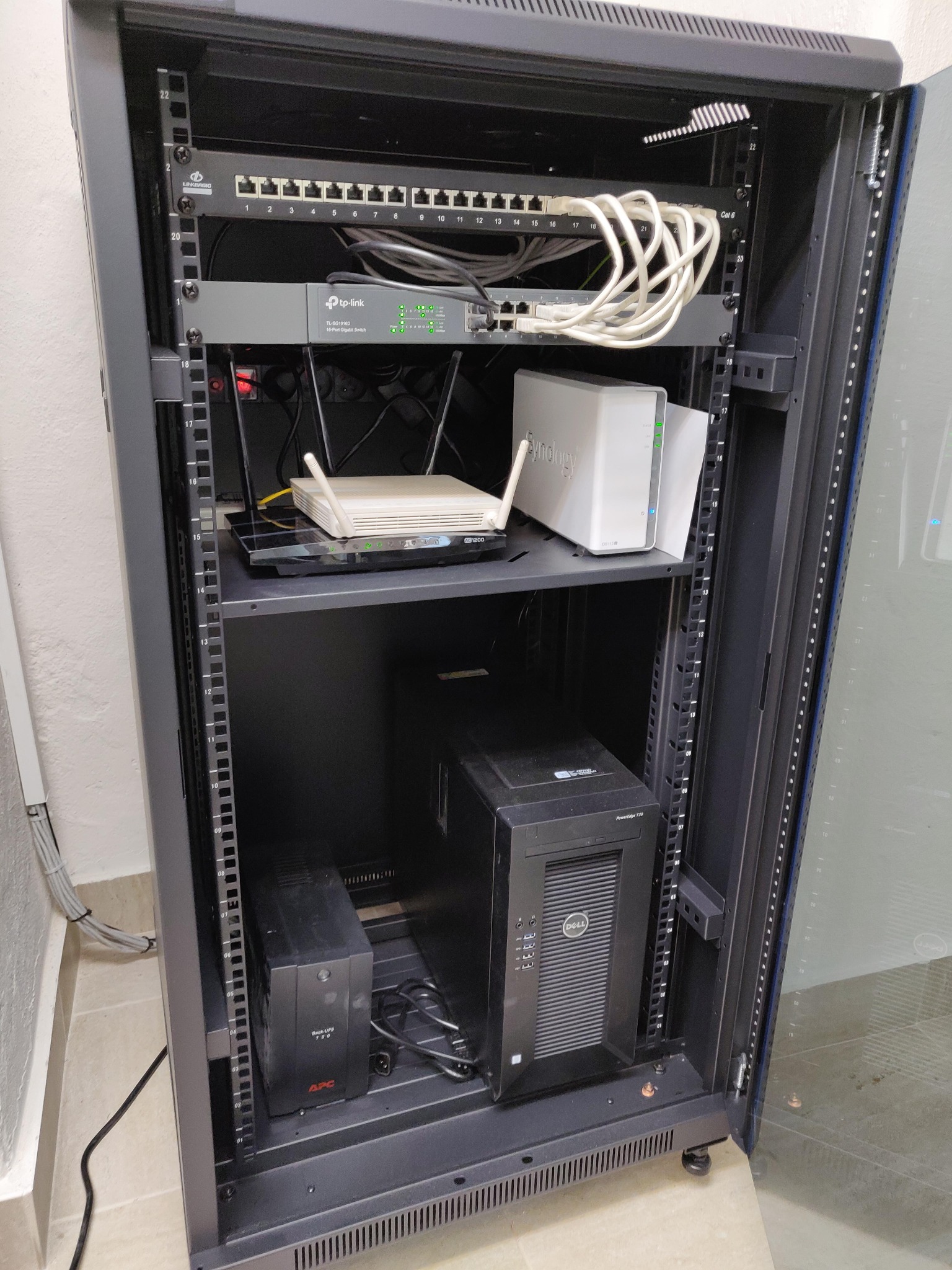 Szafa rack z zamontowanym sprzętem sieciowym: switch TP-Link, router, serwer NAS Synology, zasilacz awaryjny APC, patch panel Linkbasic i okablowanie Cat6.