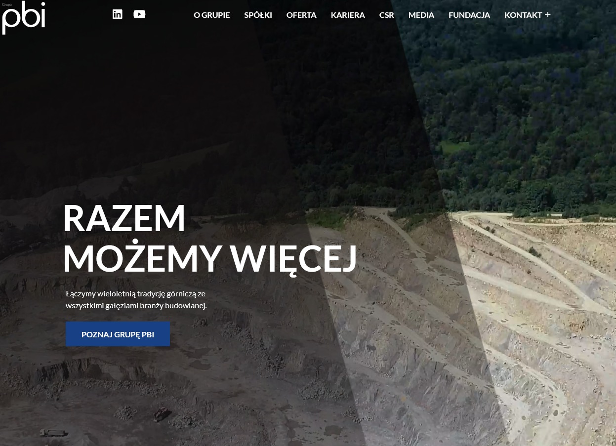 Zdjęcie z lotu ptaka przedstawiające kopalnię odkrywkową z widocznymi warstwami skalnymi i zielenią w tle, z nałożonym tekstem 'RAZEM MOŻEMY WIĘCEJ' i logo firmy PBI.