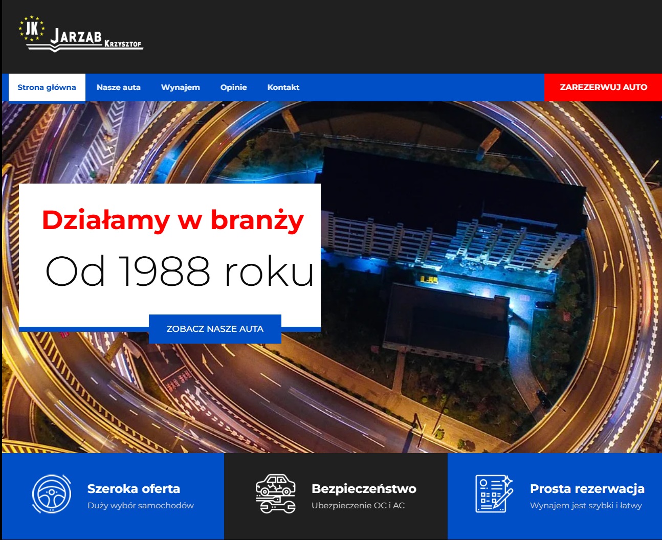 Strona internetowa firmy oferującej wynajem samochodów, z widokiem na nocną panoramę miasta i wielopoziomową autostradę w tle.