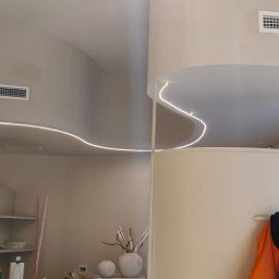 Perfect Wall - Beżowe wnętrze z dekoracyjnym oświetleniem LED na suficie, widoczny fragment dekoracji z gałęzi oraz meble.