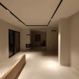 Wnętrze przestronnego, jasnego pomieszczenia z minimalistycznym wykończeniem, oświetleniem szynowym na suficie i kominkiem w oddali.