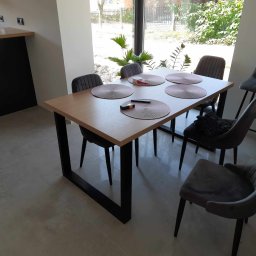 METAL FUSION - Stół z drewnianym blatem i metalowymi nogami w kształcie litery U, otoczony szarymi krzesłami i podkładkami na stole, widok z perspektywy.