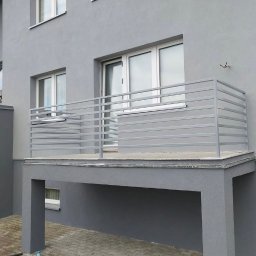 Loftski Poznań bramy przęsła balustrady - Szary balkon z prostą, poziomą balustradą ze stali nierdzewnej, widok z dołu, nowoczesna architektura.