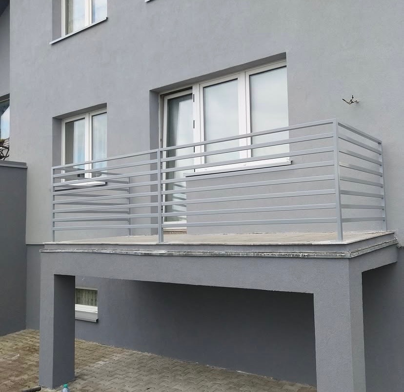 Szary balkon z prostą, poziomą balustradą ze stali nierdzewnej, widok z dołu, nowoczesna architektura.