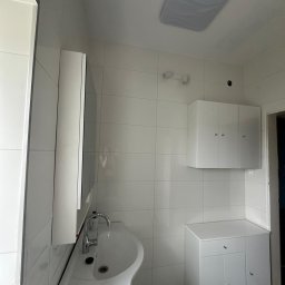 Usługi Remontowo-Budowlane DANIEL SOKOŁOWSKI-RYCHLIŃSKI - Wyremontowana, minimalistyczna łazienka w bieli z umywalką w kształcie misy, szafką pod umywalką, wiszącą szafką i płytkami ściennymi w regularną siatkę.