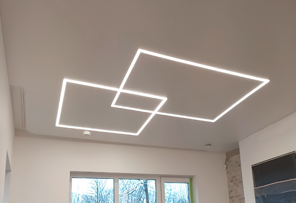 Nowoczesny sufit z oświetleniem LED w kształcie dwóch przecinających się kwadratów, widok z dołu, jasne wnętrze z oknem.