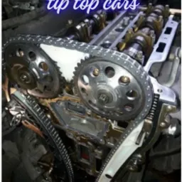 Otwarty silnik samochodowy z widocznym łańcuchem rozrządu, zębatkami i wałkami rozrządu podczas naprawy lub serwisu.