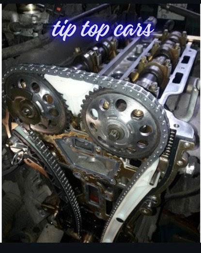 Otwarty silnik samochodowy z widocznym łańcuchem rozrządu, zębatkami i wałkami rozrządu podczas naprawy lub serwisu.