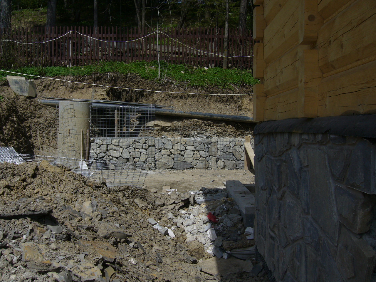 Umocnienie skarpy w Czarnym Dunajcu z wykorzystaniem gabionów i drenażu, widoczna część fundamentów domu z kamienia.