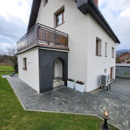 Silesia Energy - Dwukondygnacyjny dom z balkonem, wykończony w bieli i szarości, z widocznym klimatyzatorem i brukowanym podjazdem. Uwagę zwraca ciemnoszara wnęka wejściowa.