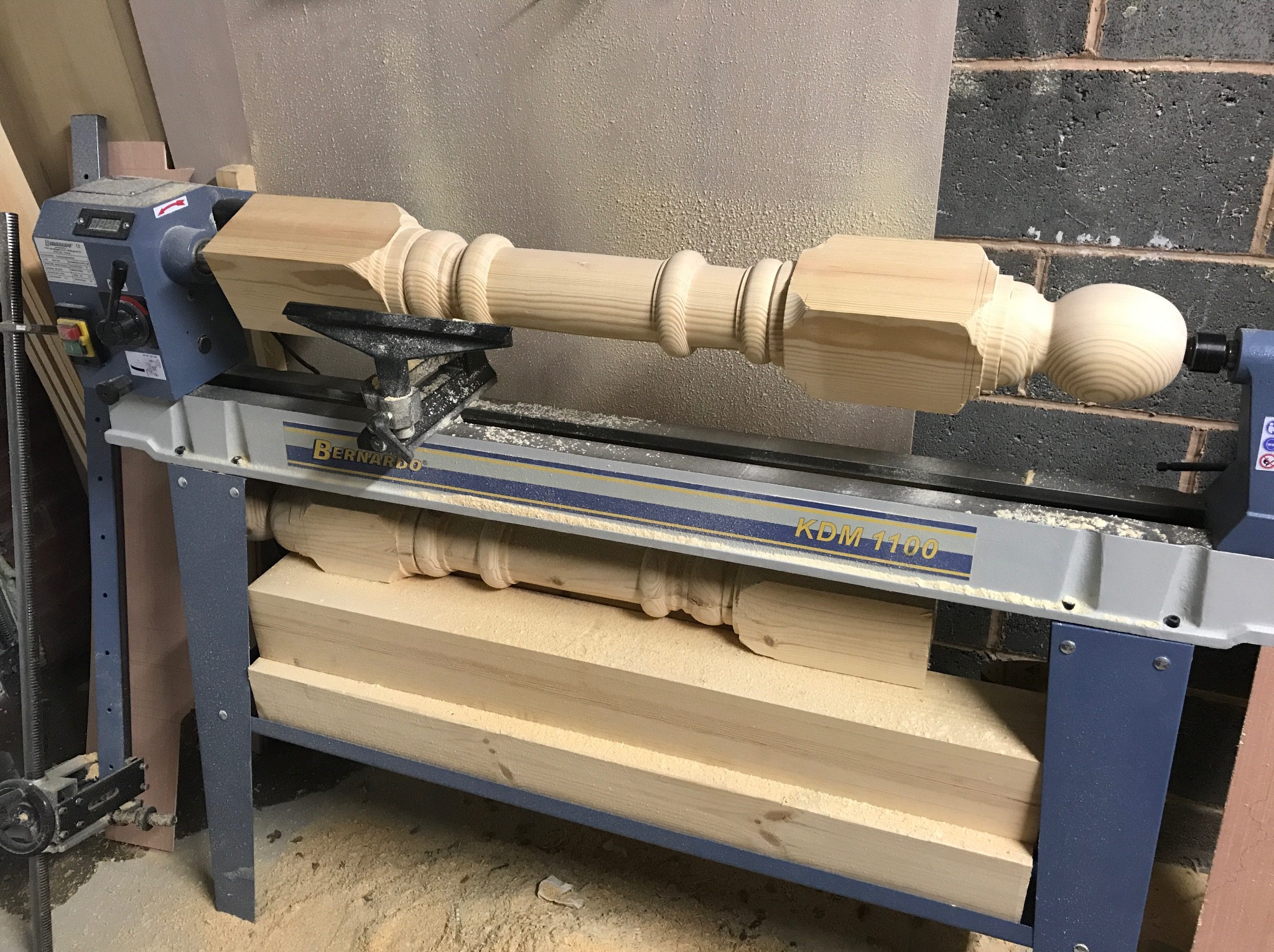 Toczenie drewnianej nogi do mebli na tokarce Bernardo KDM 1100, widoczne wióry i surowiec.