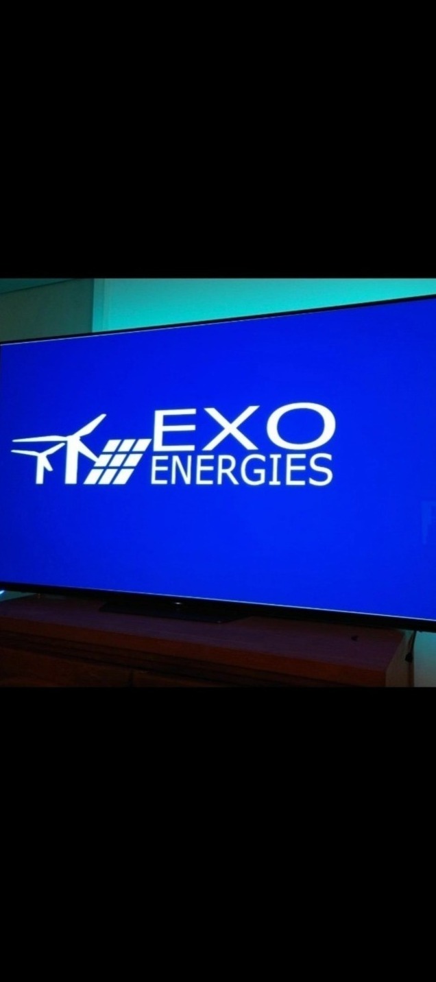 Ekran telewizora prezentujący białe logo firmy EXO Energies na niebieskim tle, z symbolem wiatraka i paneli słonecznych.