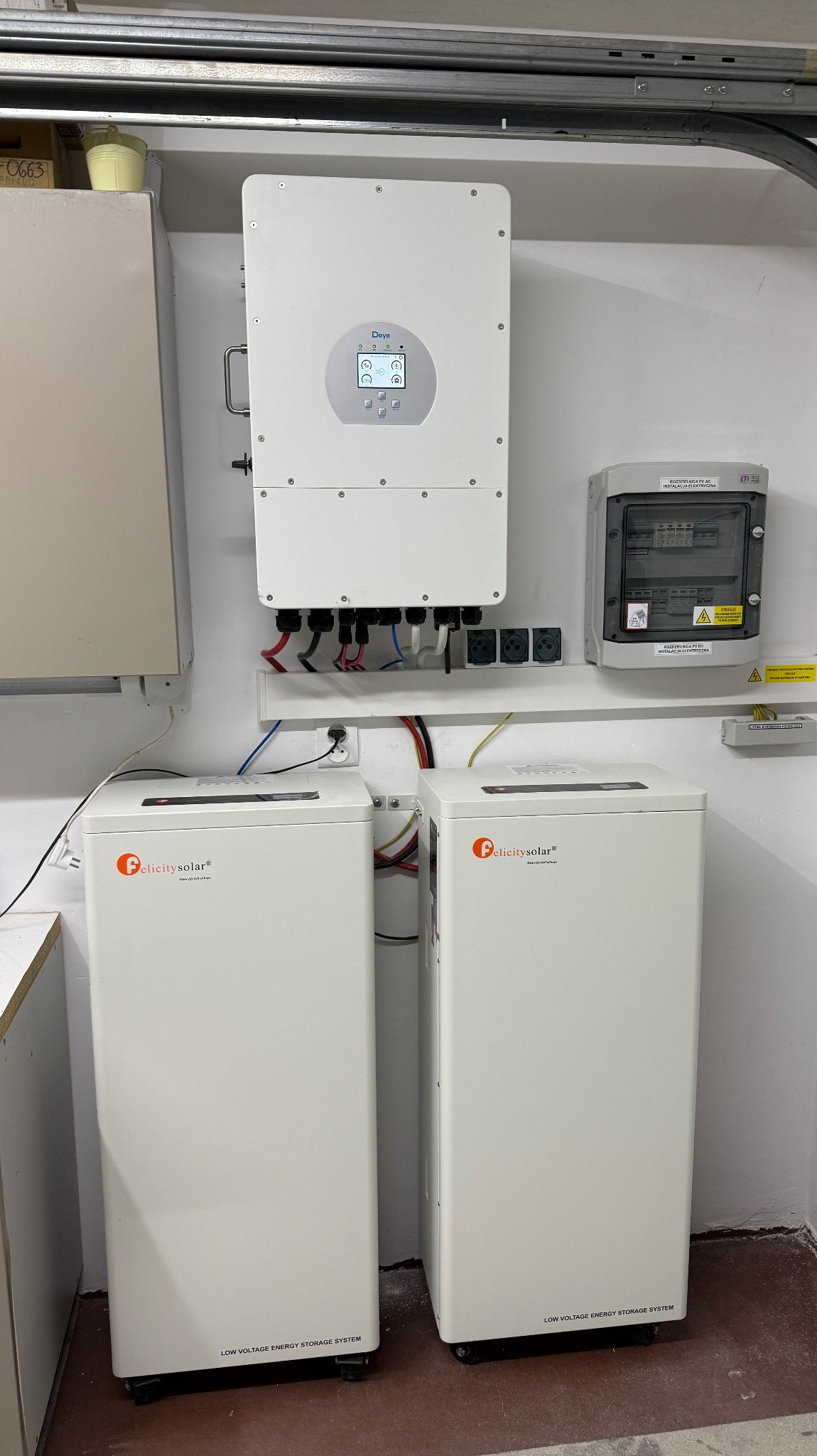 Dwa magazyny energii Felicitysolar i falownik Deye zamontowane na ścianie w garażu, z widoczną instalacją elektryczną i zabezpieczeniami.