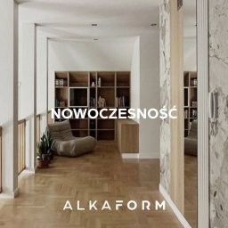 ALKAFORM - Nowoczesne wnętrze z drewnianą podłogą, regałem na książki i wygodnym fotelem, widziane z perspektywy korytarza z marmurowym wykończeniem ściany.