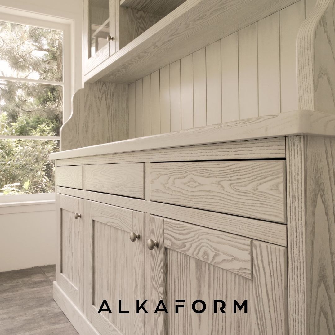 Jasna, drewniana komoda z nadstawką i szufladami, widok z boku, z logo firmy ALKAFORM na dole.