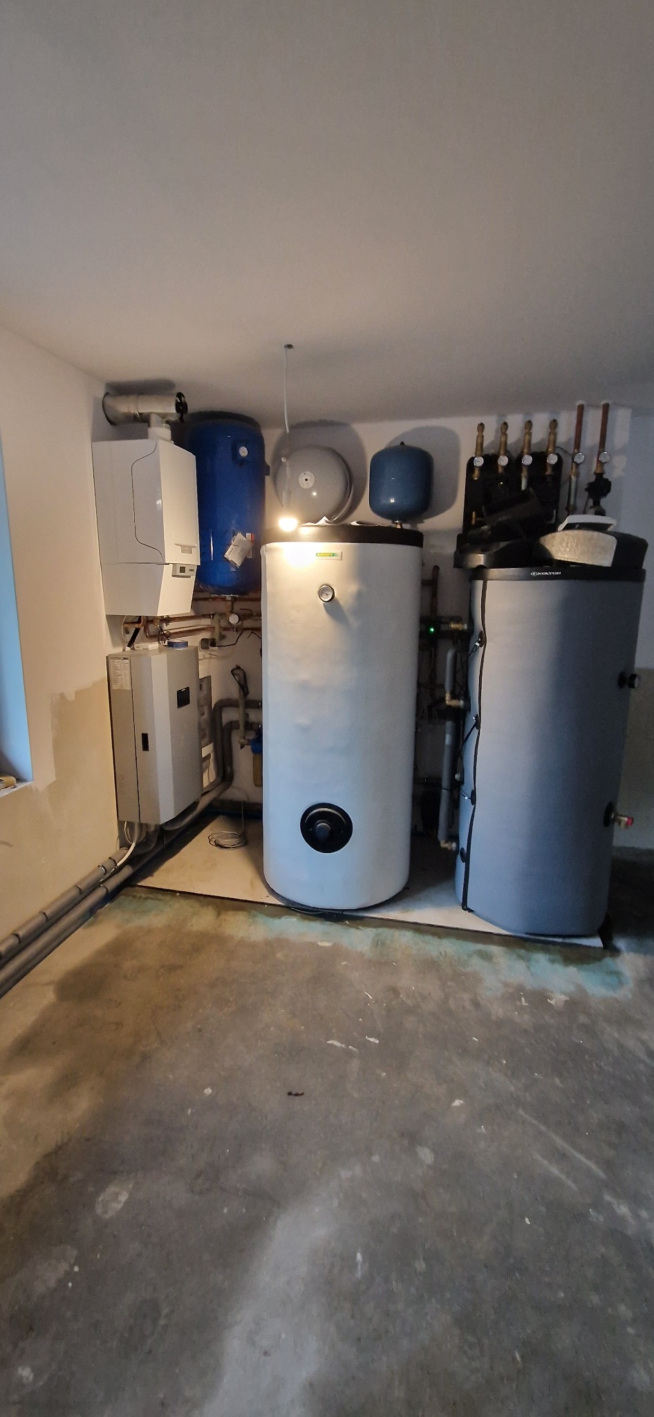 Kompletna instalacja grzewcza w piwnicy: piec gazowy, zbiorniki buforowe, pompy ciepła i orurowanie.
