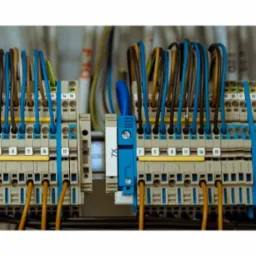 Dwa panele elektryczne z kolorowymi przewodami podłączonymi do listew zaciskowych, widoczne numery identyfikacyjne przewodów.