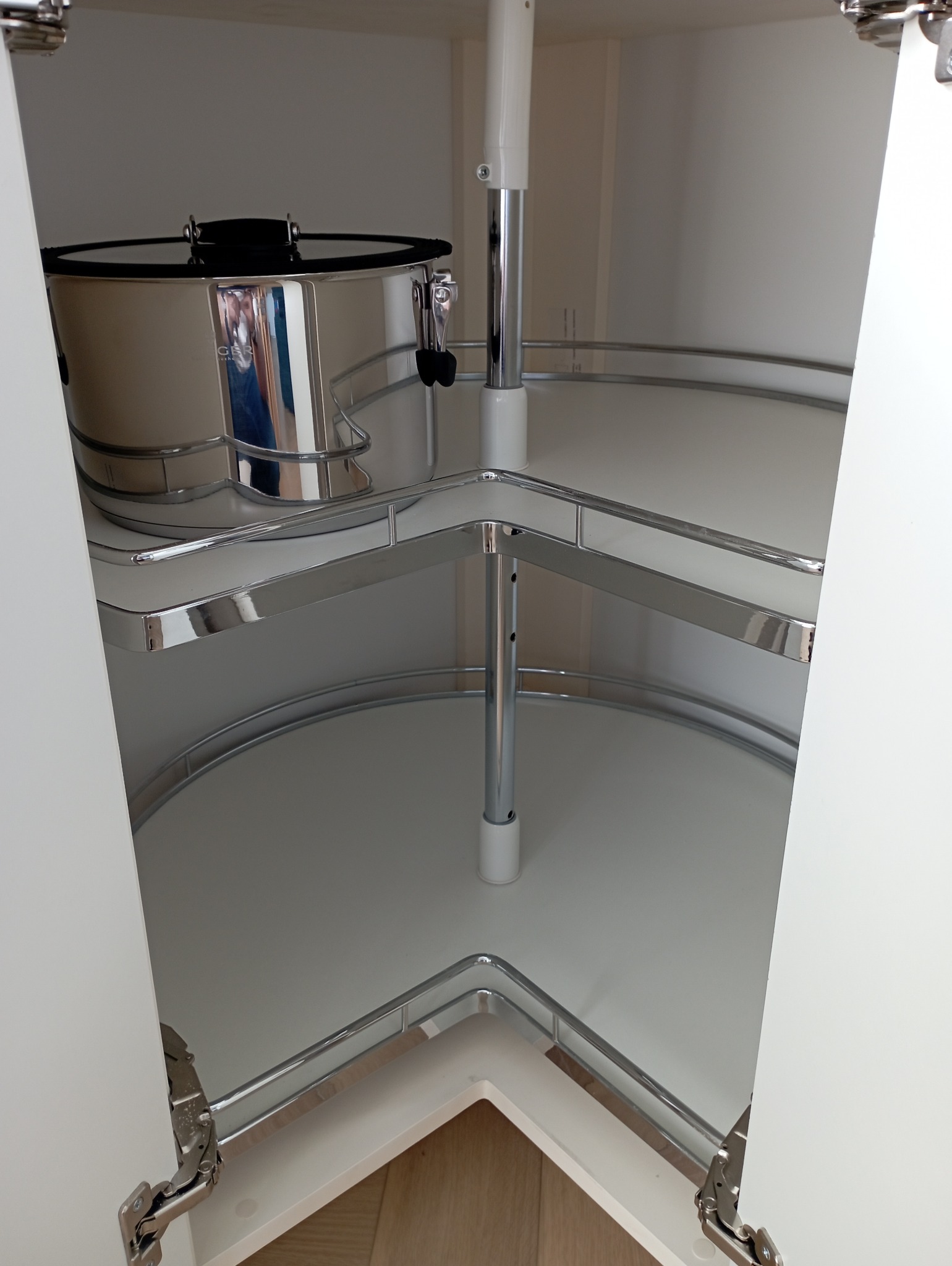 Wnętrze szafki narożnej z systemem półek obrotowych, widoczny garnek ze stali nierdzewnej na górnej półce.