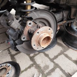 Jakub Pakulski - Zawieszenie samochodu z widoczną sprężyną i tarczą hamulcową, obok leżąca tarcza hamulcowa i klucz nastawny.