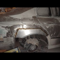 Jakub Pakulski - Fragment samochodu w trakcie naprawy blacharskiej, widoczne ślady spawania na nadkolu, szpachla i przygotowanie do lakierowania.