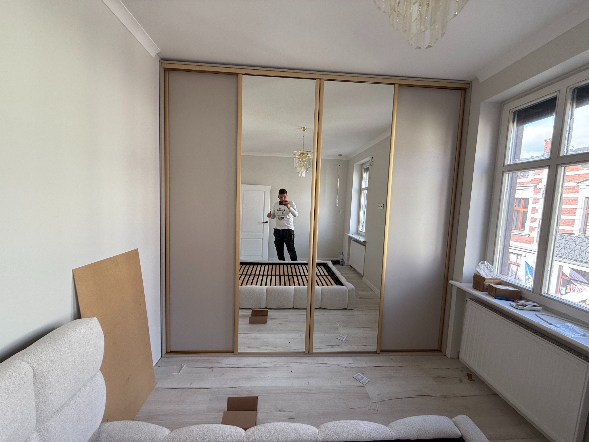 Szafa wnękowa w kolorze modnego kaszmiru z dodatkami złotych okuć oraz luster.