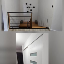 WOJCIECH MAMAK - Nowoczesne wykończenie wnętrza: białe ściany, drewniane schody z czarną balustradą i designerska lampa sufitowa. Widoczna biała przesuwna brama z przeszkleniami.