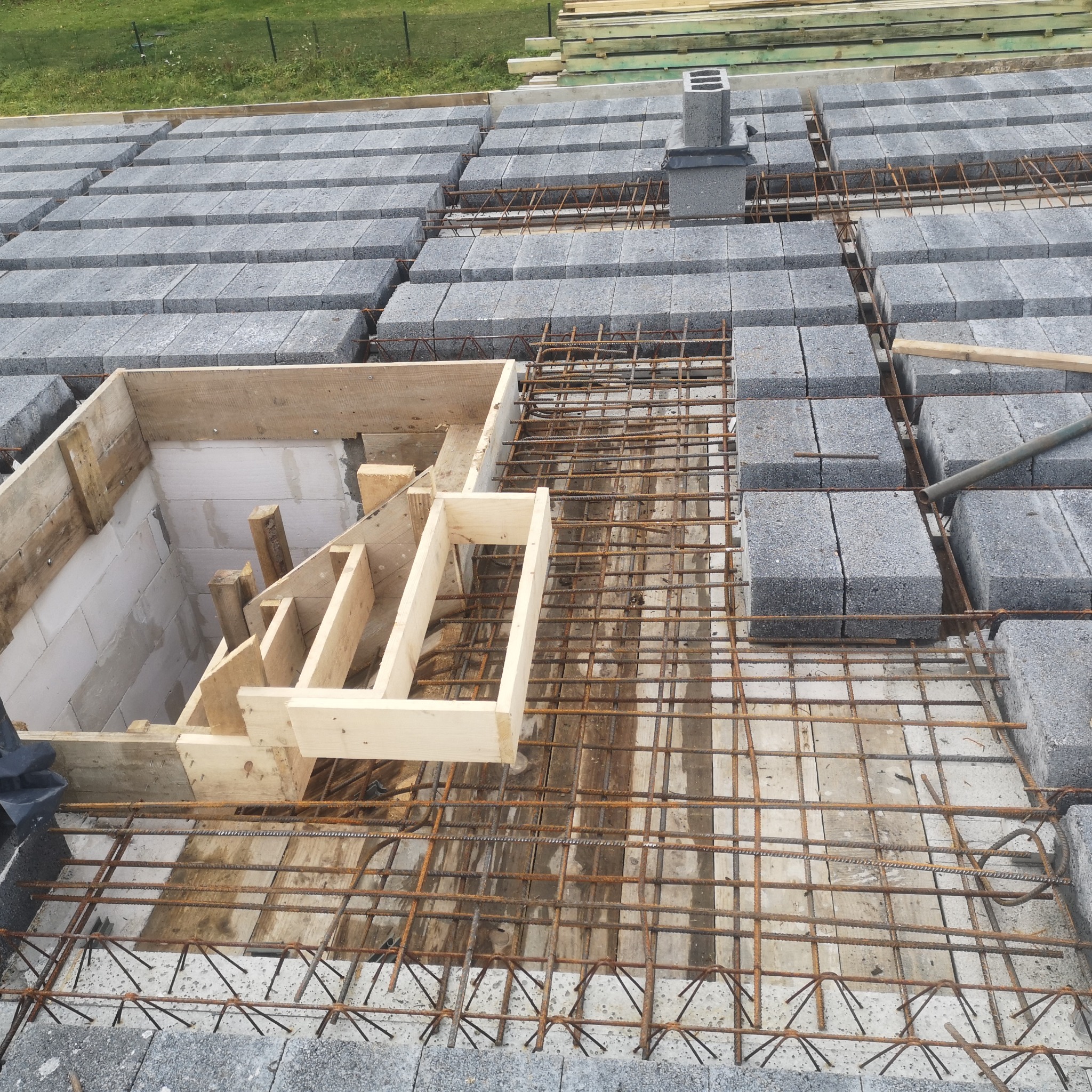 Wiązanie zbrojenia i układanie bloczków betonowych na fundamencie z przygotowanym szalunkiem pod schody.