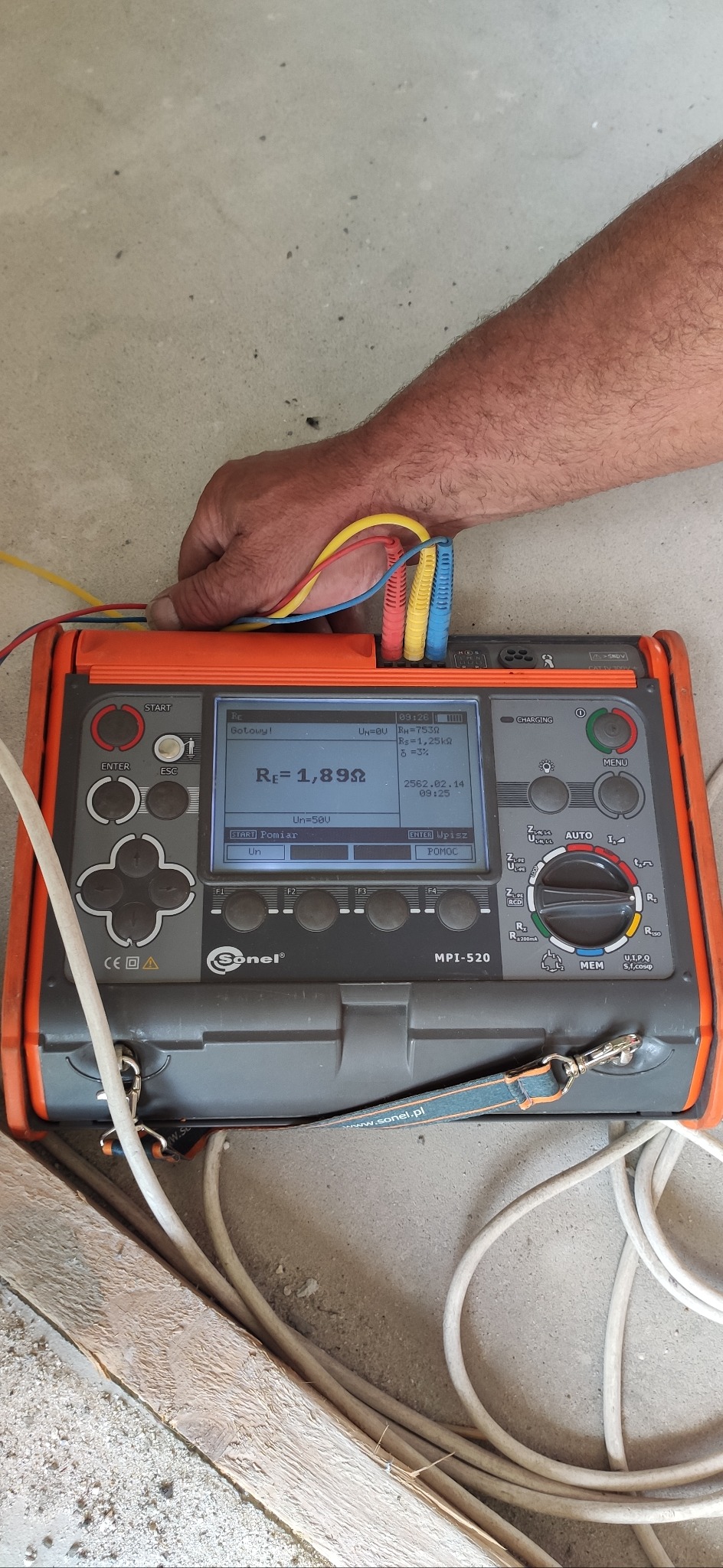 Miernik Sonel MPI-520 w trakcie pomiaru rezystancji uziemienia, z widocznymi przewodami pomiarowymi w kolorach żółtym, czerwonym i niebieskim, oraz wyświetlonym wynikiem pomiaru.
