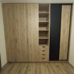 Szafa na wymiar z przesuwnymi drzwiami, fronty w odcieniach drewna, czarny panel, półki i szuflady. Podłoga drewniana w jodełkę, minimalistyczny design.