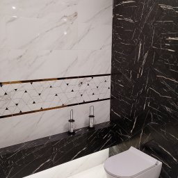 GRUPA FLEXIBLE SPÓŁKA Z OGRANICZONĄ ODPOWIEDZIALNOŚCIĄ - Nowoczesna łazienka z białymi marmurkowymi płytkami, pasem dekoracyjnym z geometrycznym wzorem i czarną ścianą z płytek imitujących marmur ułożonych w jodełkę, podświetlona listwa LED pod blatem...