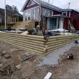 MAR-BUD CONSTRUCTION - Budowa tarasu z drewnianą palisadą zabezpieczającą ziemię, widoczne narzędzia i materiały budowlane na placu budowy.