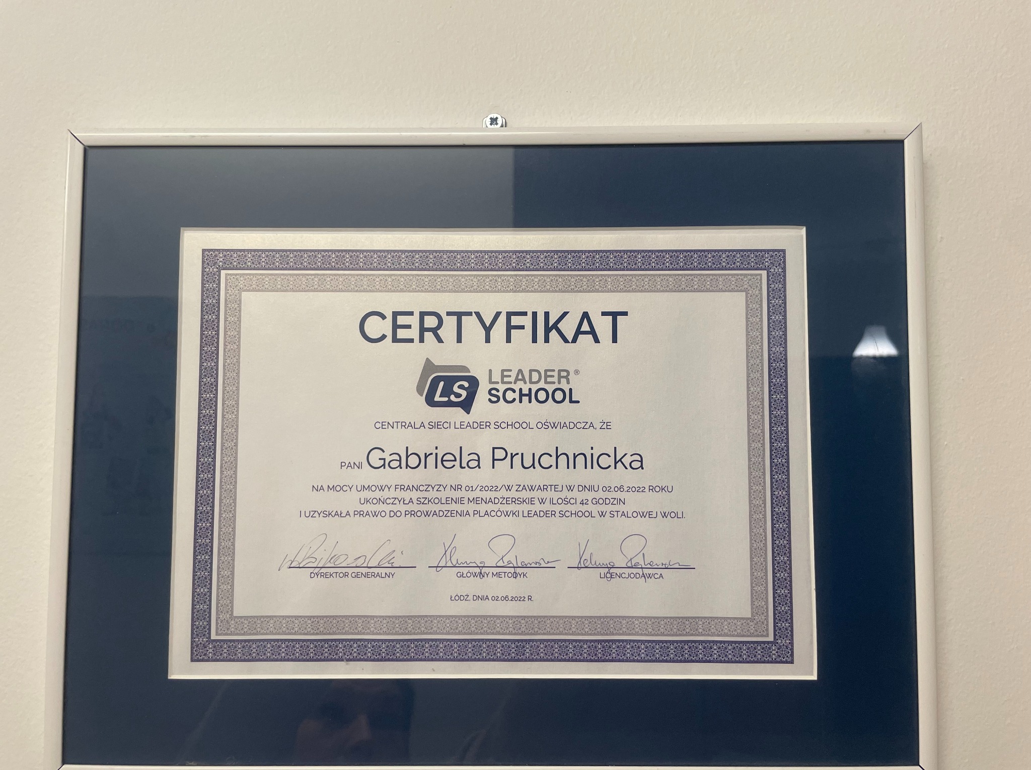 Oprawiony w ramkę certyfikat Leader School dla Gabrieli Pruchnickiej, potwierdzający ukończenie szkolenia menadżerskiego i prawo do prowadzenia placówki w Stalowej Woli, z podpisami dyrektora...