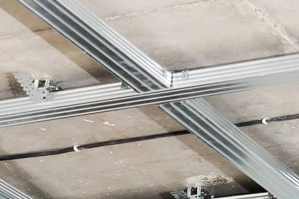 Metalowa konstrukcja sufitu podwieszanego zamocowana do surowego stropu, widoczne profile i elementy montażowe.