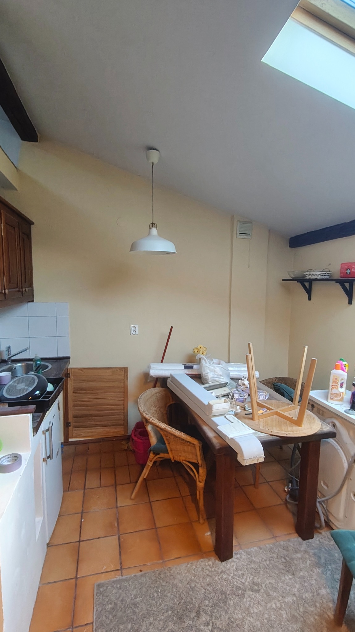 Wnętrze kuchni w trakcie remontu: widoczne przygotowania do prac wykończeniowych, materiały budowlane na stole, ściany w jasnym odcieniu przed malowaniem.