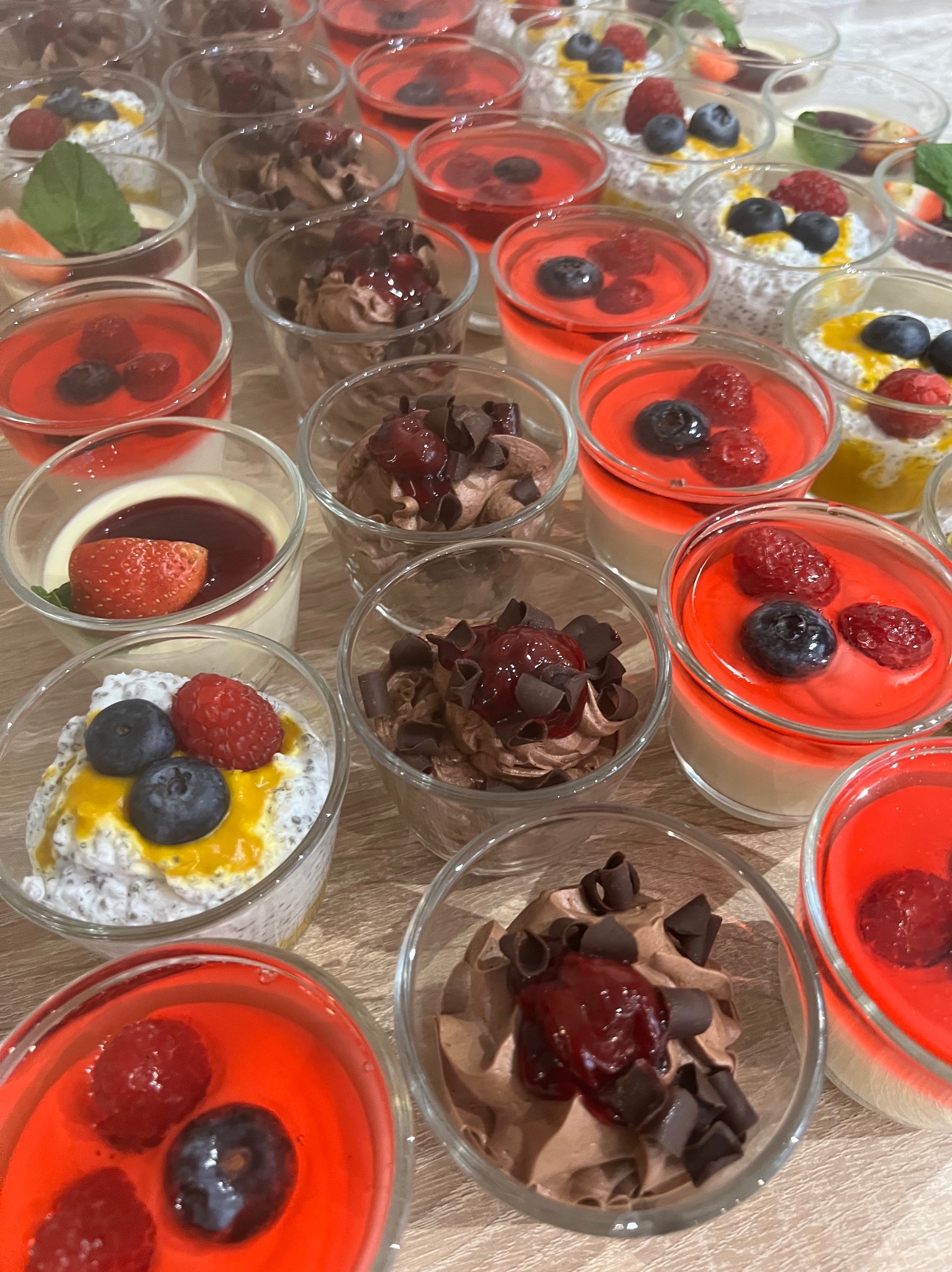 Deserki w szklanych pucharkach z owocami i czekoladą, prezentowane przez catering z Warszawy. Różnorodne kompozycje smakowe i kolorystyczne, idealne na imprezy.