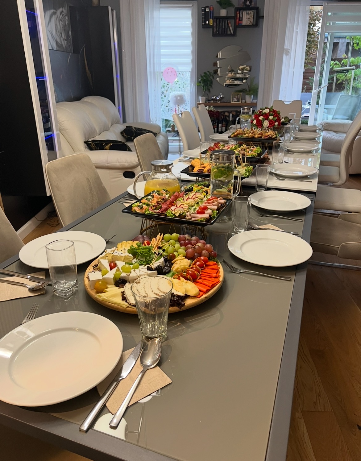 Uroczysty stół z zastawą, przekąskami i napojami, gotowy na przyjęcie gości w jasnym wnętrzu. Elegancki catering na stole.