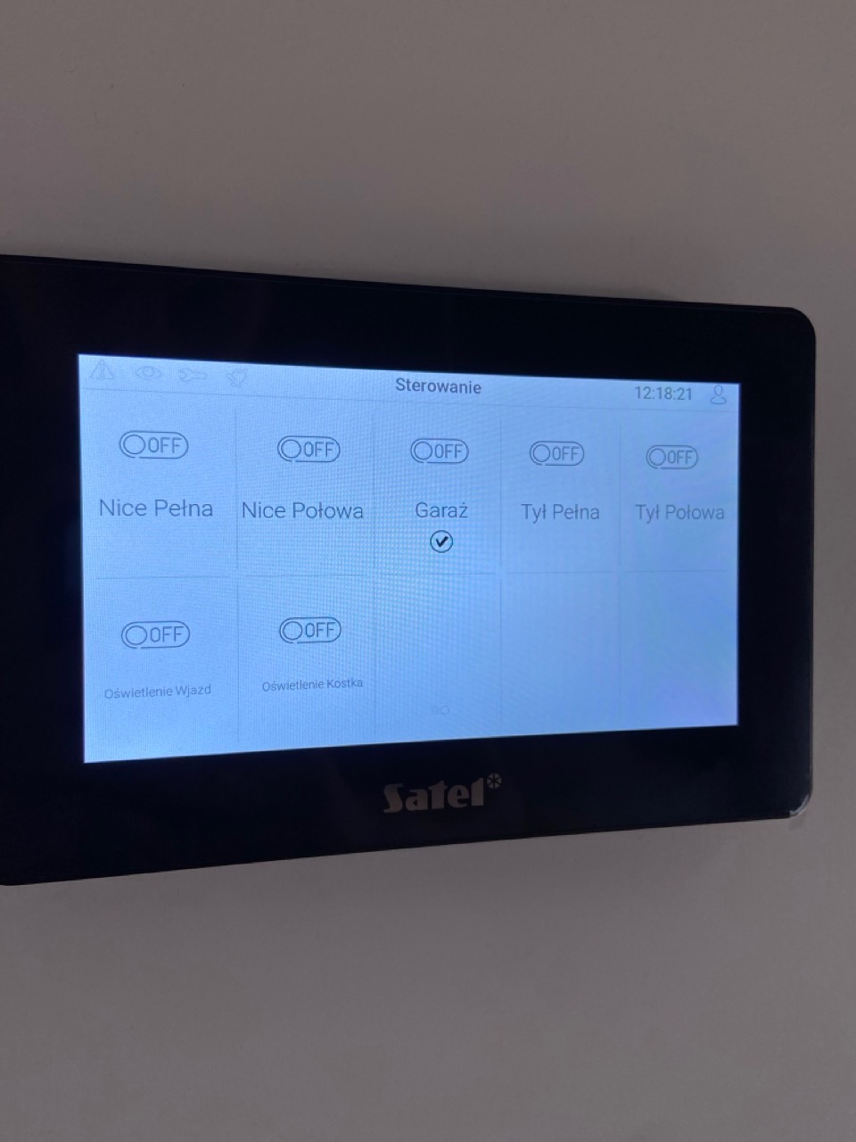 Panel sterowania systemem alarmowym Satel z włączoną opcją 'Garaż', wyświetlający status oświetlenia posesji.
