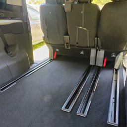 Jacek Szupryczyński - Wnętrze busa z systemem szynowym do mocowania foteli. Widoczne szyny w podłodze i mocowania ISOFIX. Otwarte drzwi boczne pojazdu.