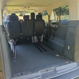 Jacek Szupryczyński - Wnętrze szarego busa z widocznymi szynami do mocowania foteli i przestrzenią bagażową. Fotele ustawione w konfiguracji dla pasażerów.