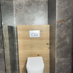 ANDRII DUBYNSKYI BUD - Nowoczesna łazienka z szarą marmurową płytką, drewnianą zabudową stelaża WC i szklaną kabiną prysznicową.