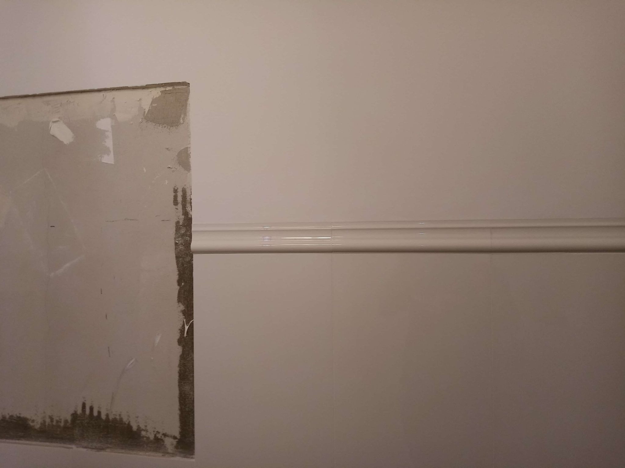 Fragment ściany: przygotowana do położenia płytek (z lewej) i wykończona z listwą dekoracyjną (z prawej). Etap prac wykończeniowych.