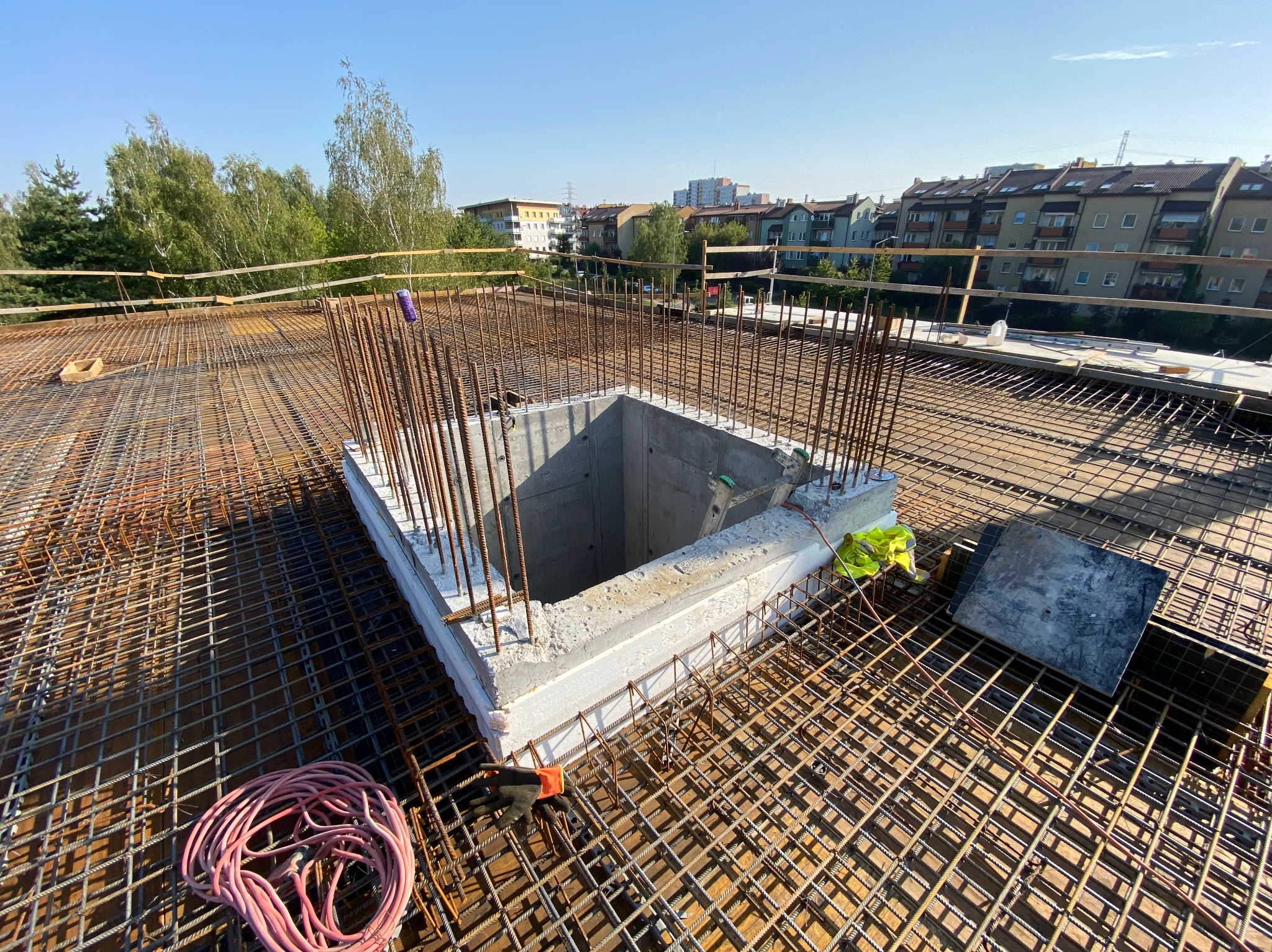 Szare, betonowe wzmocnienie szybu na zbrojeniu stropu, widok z góry, w tle zabudowa miejska i zieleń.