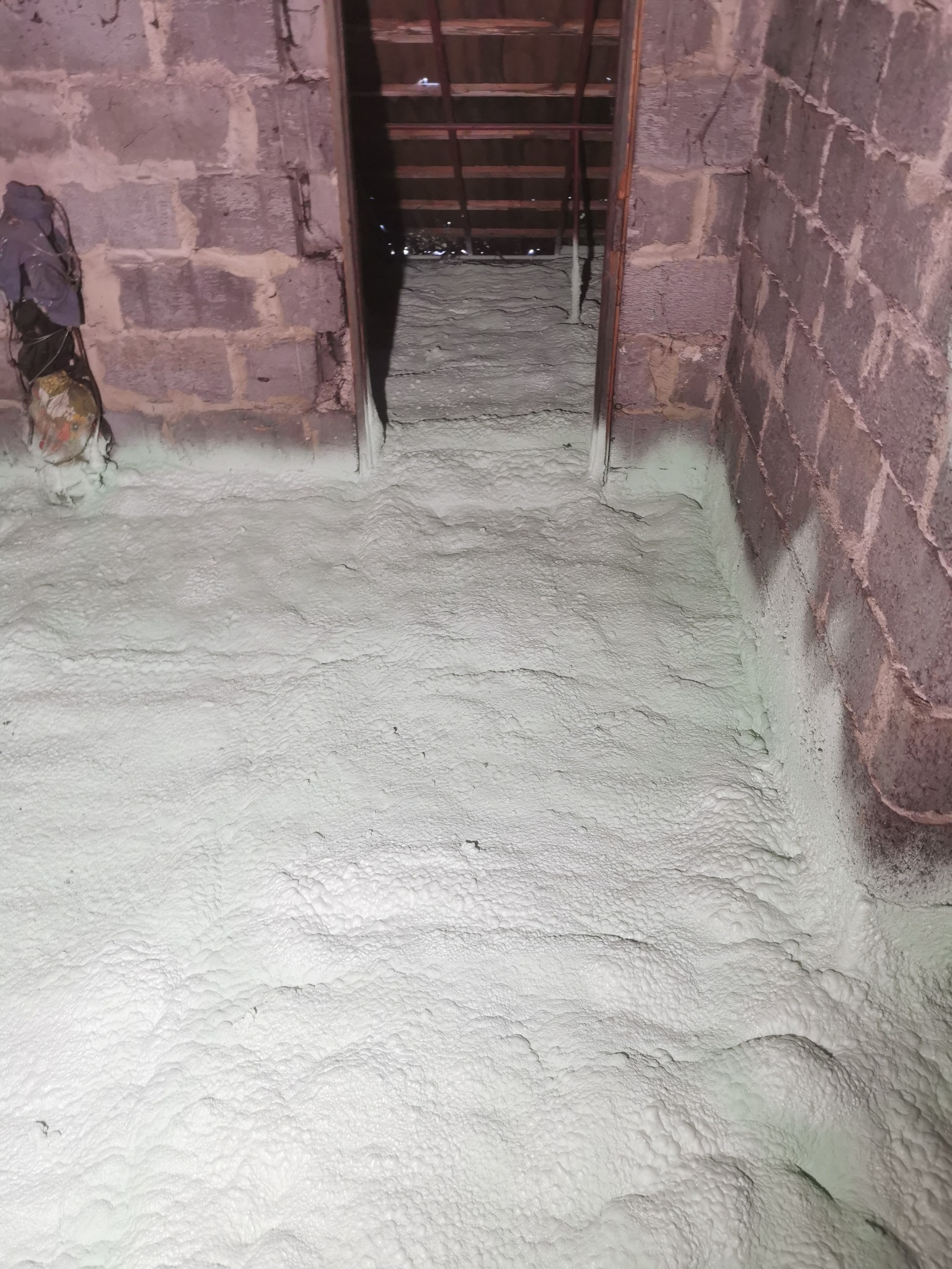 Poddasze po aplikacji pianki PUR w Króliku Polskim. Widoczne bloki betonowe ściany i równomierna warstwa izolacji w kolorze jasnej zieleni.