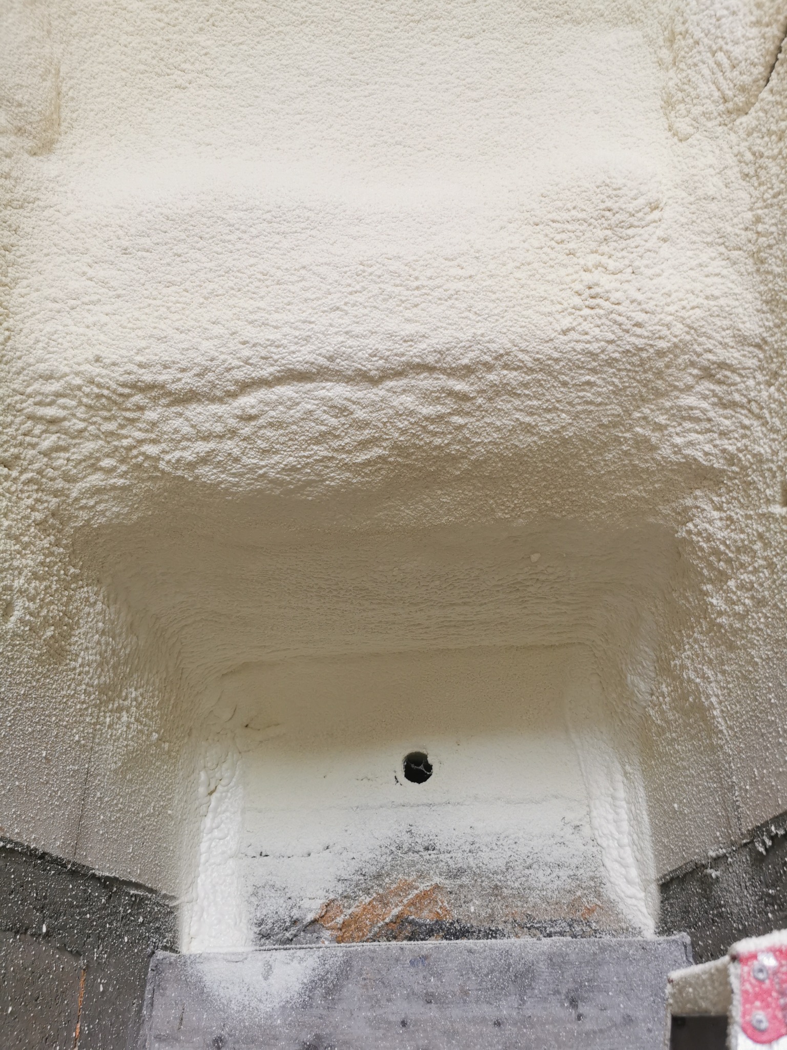 Szczegółowe ujęcie izolacji pianką PUR w przestrzeni ograniczonej betonowymi elementami, widoczny otwór wentylacyjny.