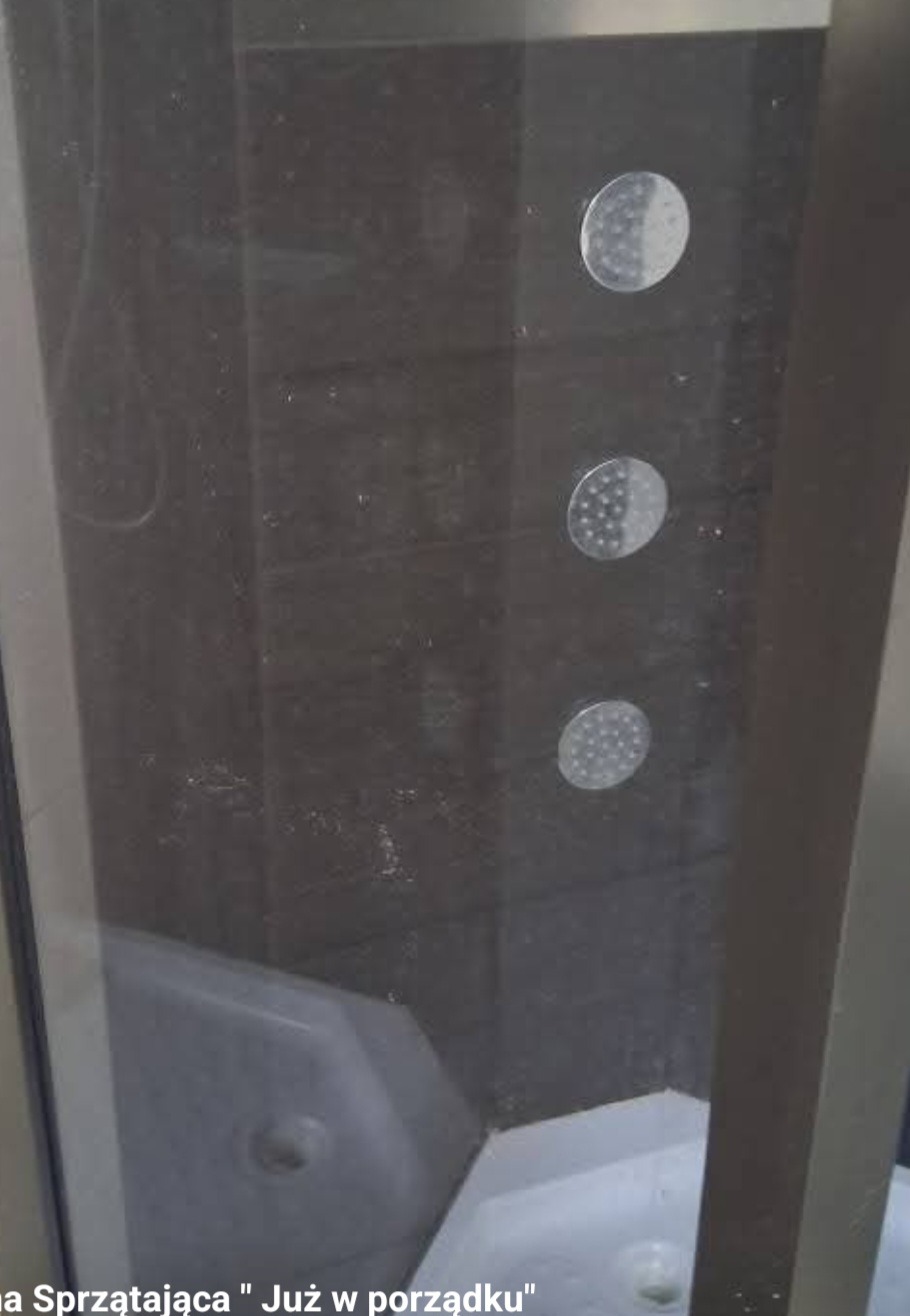 Brudna kabina prysznicowa z widocznymi zaciekami na szkle i osadem na dyszach, wymagająca dokładnego czyszczenia.